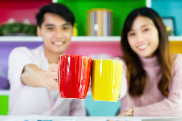 Junge Kollegen, die während des Arbeitens Getränk trinken