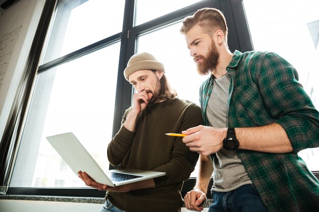 Junge konzentrierte Männerkollegen im Büro mit Laptop