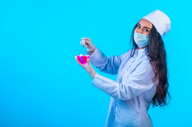 Junge Krankenschwester in isolierter Uniform, die eine Testflasche hält und lächelt.