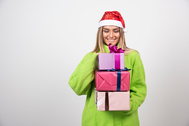 Junge lächelnde Frau, die in den Händen festliche Weihnachtsgeschenke hält