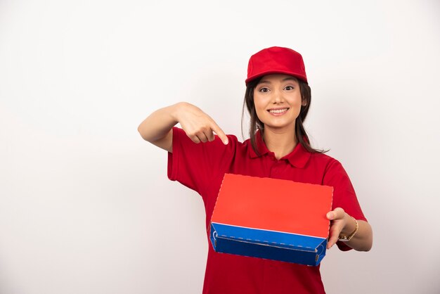 Junge lächelnde Frau in der roten Uniform, die Pizza im Kasten liefert.