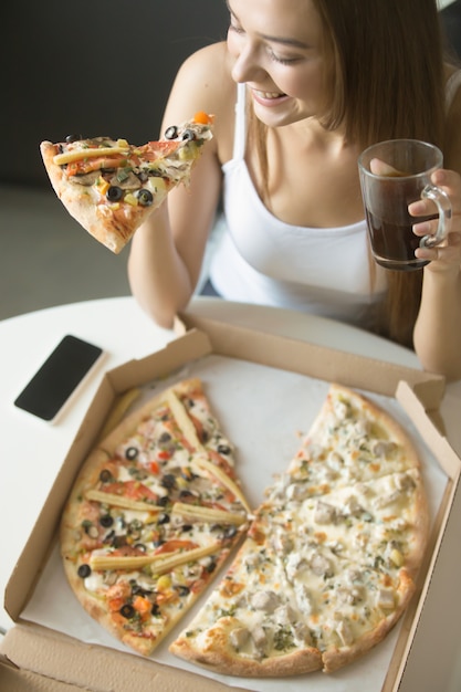 Junge lächelnde Frau mit einer Scheibe Pizza