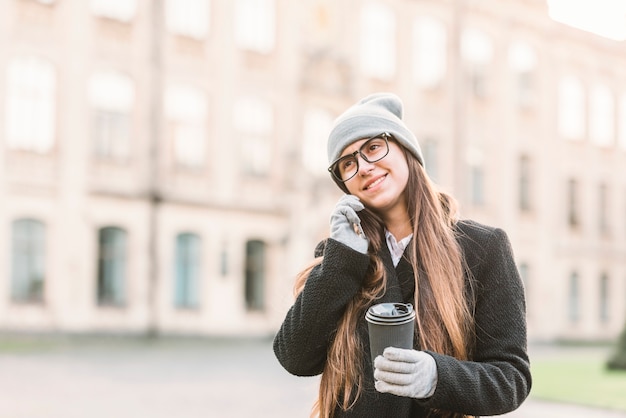 Junge lächelnde Frau mit Schale sprechend auf Smartphone auf Straße