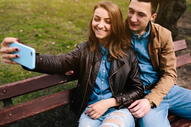 Junge lächelnde Paare, die ein Foto auf einer Bank unter