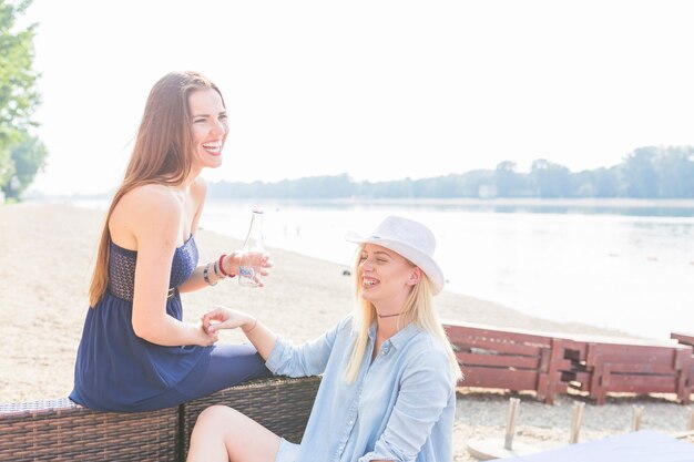 Junge lächelnde weibliche Freunde, die am Strand genießen