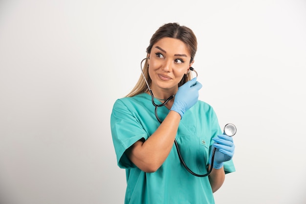 Junge lächelnde weibliche Krankenschwester, die mit Stethoskop aufwirft.