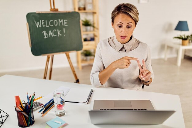 Junge Lehrerin benutzt Laptop und erklärt ihren Schülern online eine Lektion