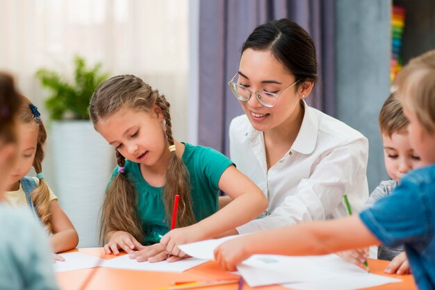 Junge Lehrerin hilft ihren Schülern im Unterricht