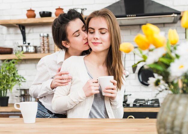Junge lesbische Frau, die ihre Freundin in der Hand hält Kaffeetasse liebt