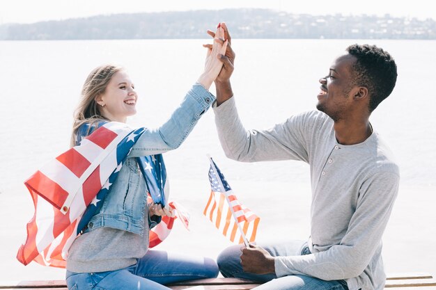 Junge Leute, die Hoch fünf beim Halten der amerikanischen Flagge geben