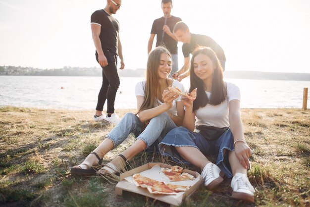 Junge Leute, die Pizza essen und Shisha am Strand rauchen