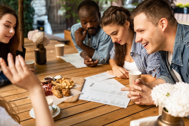 Junge leute lernen das menü, bevor sie im kleinen gemütlichen open-air-café bestellen