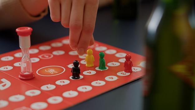 Junge Leute spielen Scharaden-Brettspiele mit Figuren, würfeln für Kartenspiele. Männer und Frauen genießen den Strategiewettbewerb, um Karten für Unterhaltung und Spaß zu erraten. Nahansicht.