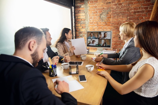 Junge Leute sprechen, arbeiten während der Videokonferenz mit Kollegen im Büro oder im Wohnzimmer