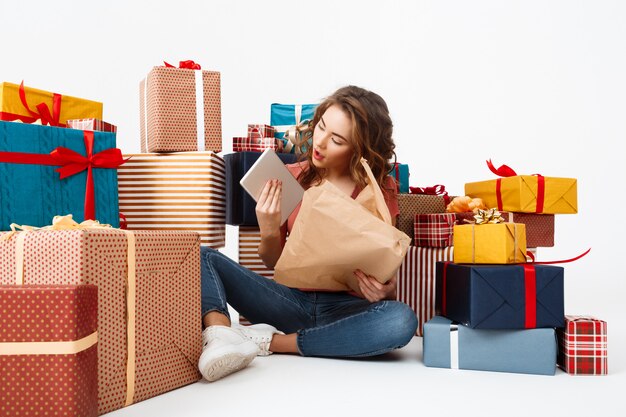 Junge lockige Frau, die auf Boden unter Geschenkboxen öffnet, die Geschenke öffnen