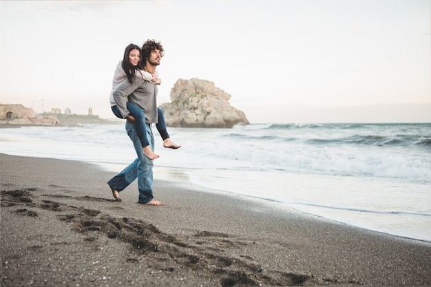 Junge Mädchen klettern auf den Rücken eines Mannes am Strand