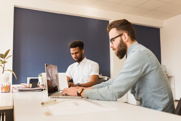 Junge Männer, die Laptope im Büro durchstöbern