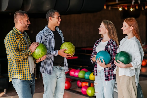 Kostenloses Foto junge männer und frau, die in einem bowlingspielverein stehen