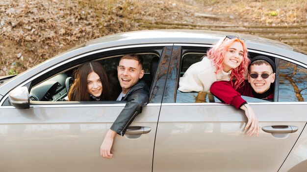 Junge Männer und Frauen, die aus Autofenster heraus schauen