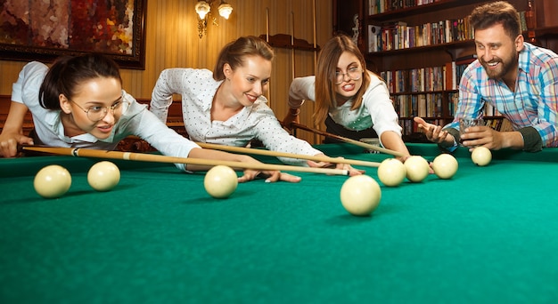 Junge Männer und Frauen spielen Billard im Büro nach der Arbeit.