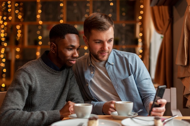 Junge männliche Freunde, die auf Mobile schauen