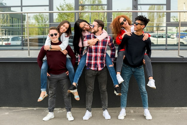 Kostenloses Foto junge männliche freunde, die piggyback zu ihren freundinnen tragen