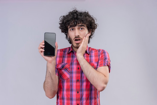 Junge männliche lockige Haare isoliert buntes Hemd Smartphone schockiert