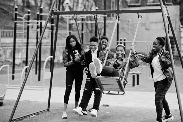 Junge Millennials afrikanische Freunde auf Spielplatzrutsche und Schaukel Fröhliche schwarze Menschen, die gemeinsam Spaß haben Freundschaftskonzept der Generation Z