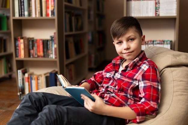 Kostenloses Foto junge mit buch, das kamera betrachtet