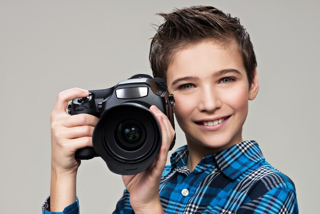 Junge mit Fotokamera, die Bilder macht. Porträt des kaukasischen Jungen mit der Digitalkamera in den Händen