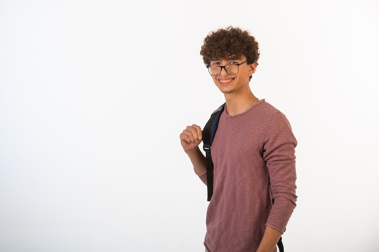 Kostenlose Foto junge mit lockigem haar in einer optischen brille hält seinen rucksack und ist bereit für die ausbildung.