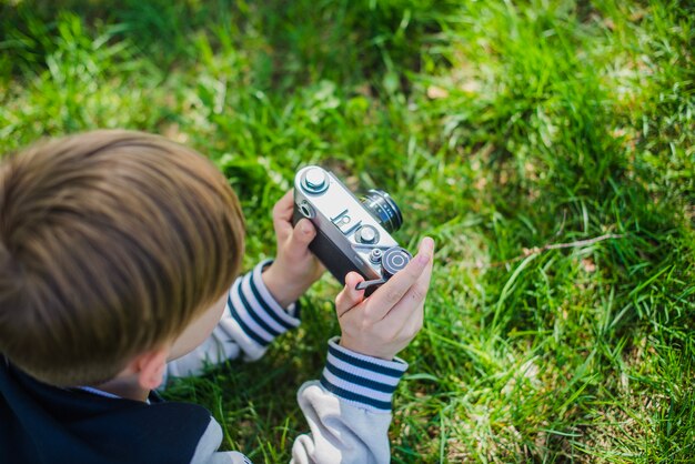 Junge mit seiner Kamera auf dem Rasen liegen