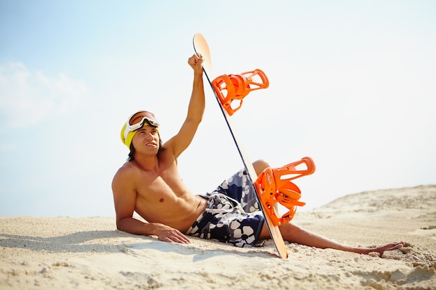 Junge mit Snowboard am Strand