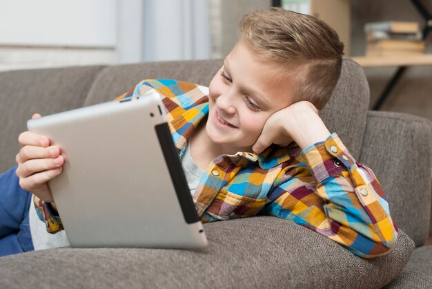 Junge mit Tablette auf Couch