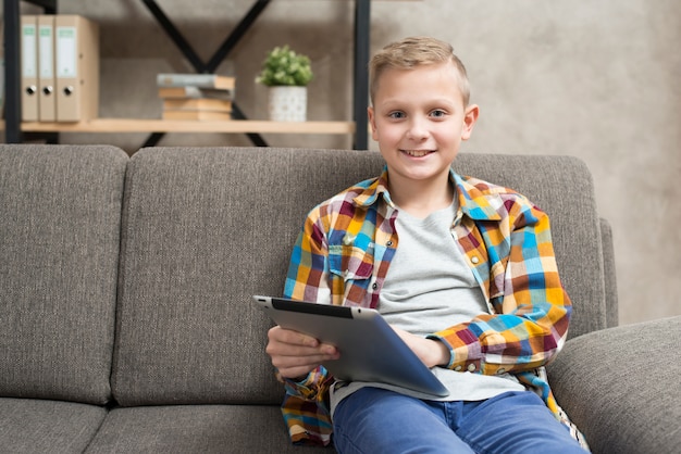 Junge mit Tablette auf Couch