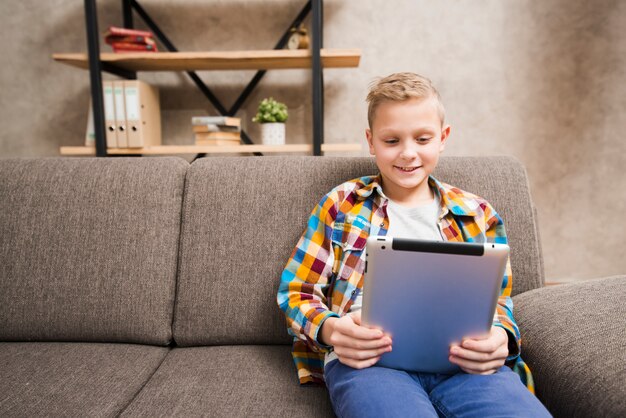 Junge mit Tablette auf Couch