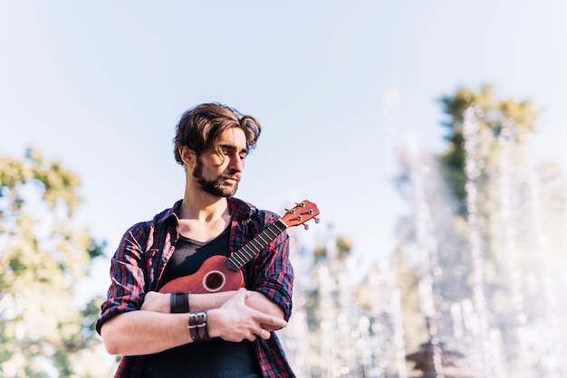 Junge mit Ukelele vor einem Brunnen