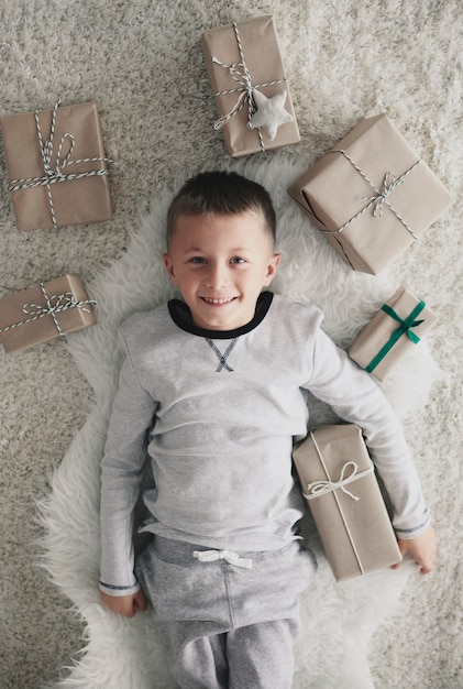 Kostenloses Foto junge mit weihnachtsgeschenk auf dem rücken liegend