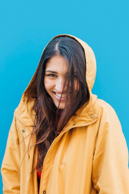 Junge moderne Frau, die gelben Hoodie vor blauem Hintergrund trägt