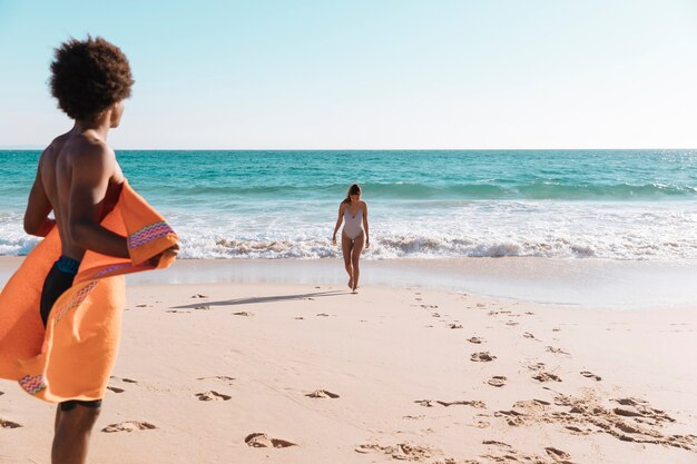 Junge multiethnische Paare, die auf Strand sich entspannen