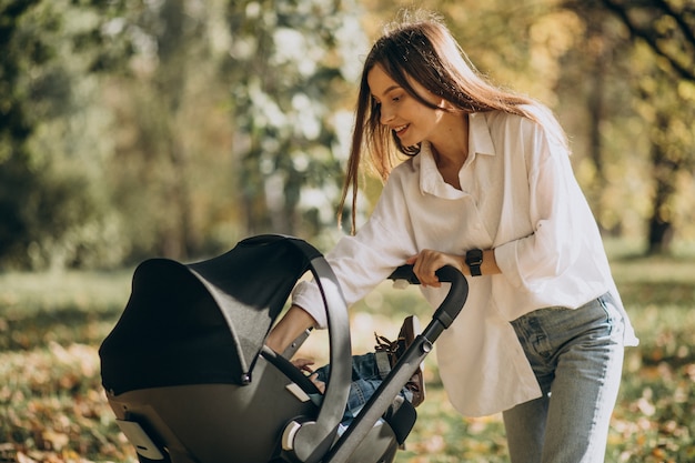 Kostenloses Foto junge mutter, die mit kinderwagen geht