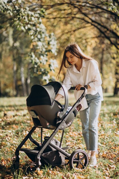 Junge Mutter, die mit Kinderwagen geht