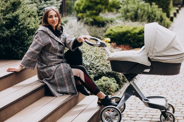 Junge Mutter, die mit Kinderwagen im Hinterhof geht