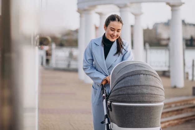 Kostenloses Foto junge mutter, die mit kinderwagen im park geht