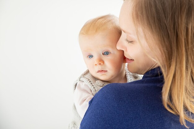 Junge Mutter, die niedliches Säuglingskind umarmt