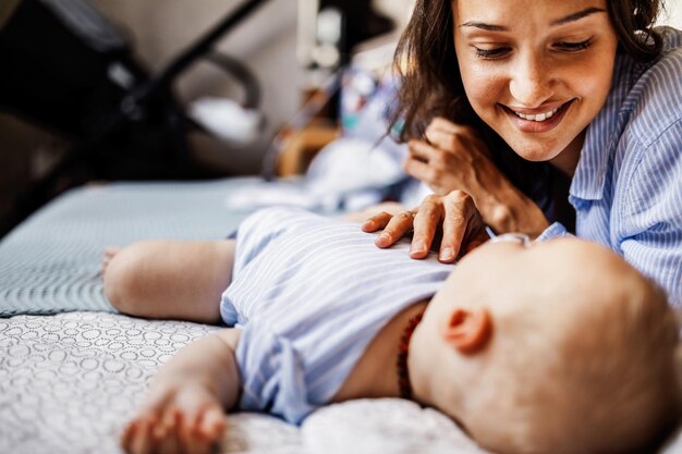 Junge Mutter genießt, während sie ihr Baby beim Schlafen auf dem Bett beobachtet