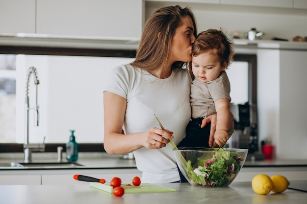Junge Mutter mit ihrem kleinen Sohn, der Salat in der Küche macht