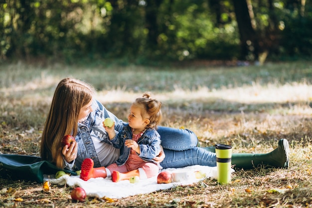 Junge Mutter mit ihrer kleinen Tochter in einem Herbstpark, der Picknick hat
