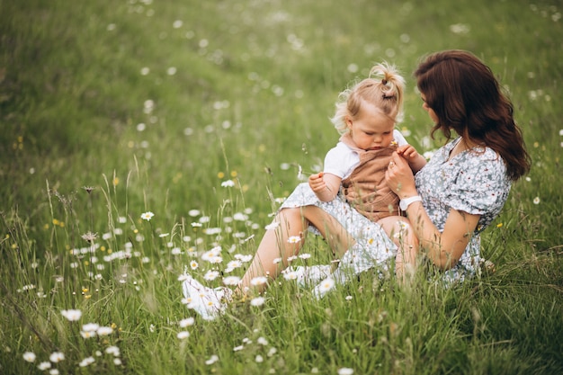 Junge Mutter mit kleiner Tochter im Park, der auf Gras sitzt
