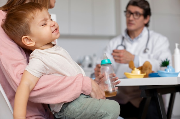 Junge mutter mit kleinkind beim kinderarzt zur beratung